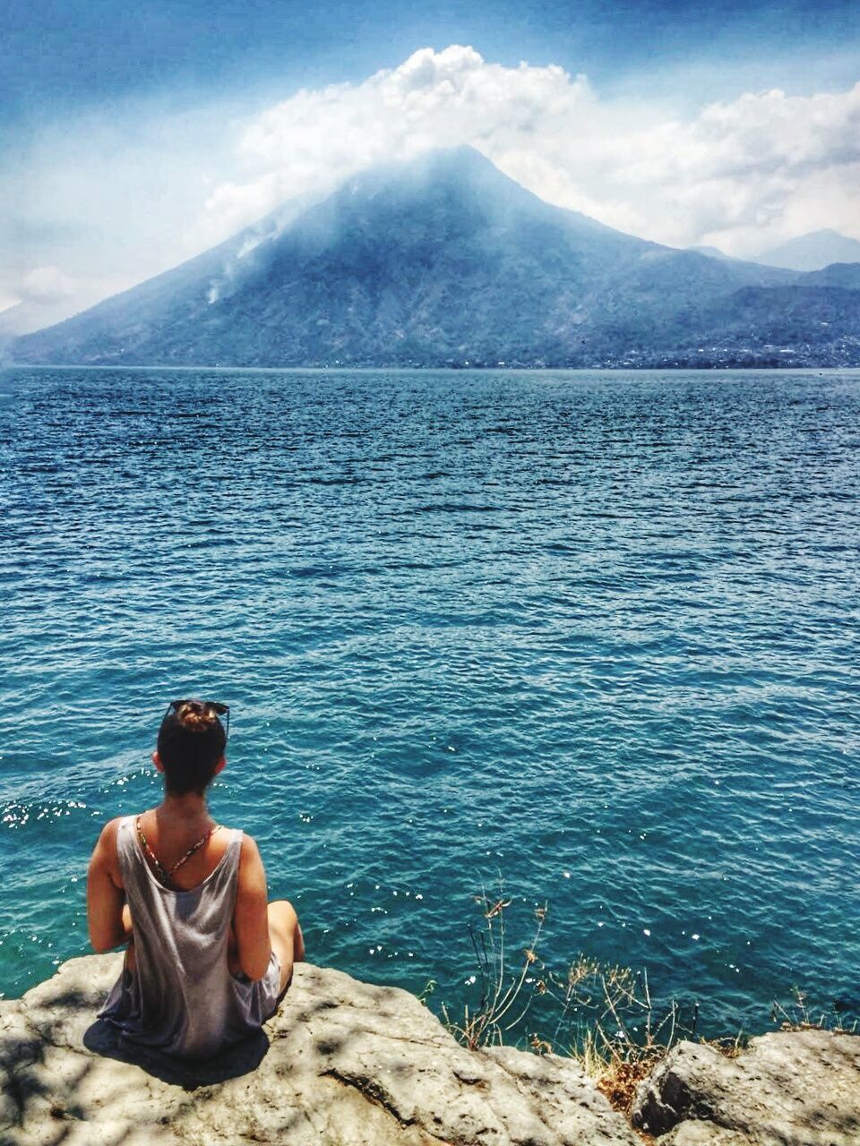 water, leisure activity, mountain, one person, beauty in nature, lifestyles, shirtless, scenics - nature, nature, sky, real people, sitting, day, tranquility, tranquil scene, relaxation, cloud - sky, rear view, outdoors, looking at view