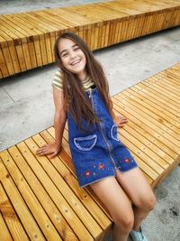 Portrait of smiling girl sitting on wood