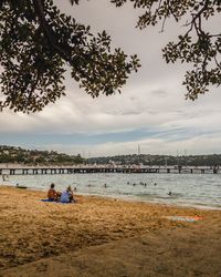 People relaxing on beach against sky