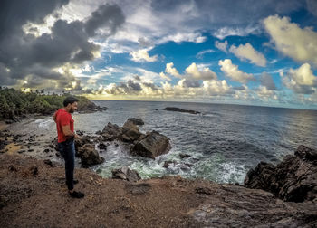 Rear view of person standing on beach against sky