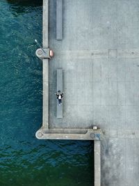 High angle view of woman lying on bench at promenade by sea