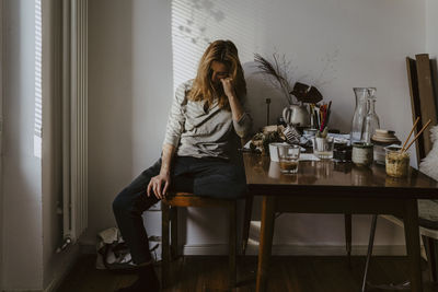 Young woman sitting on table at home