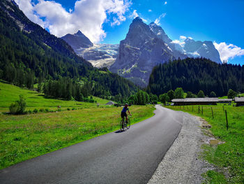 Rear view of man riding motorcycle on road against sky