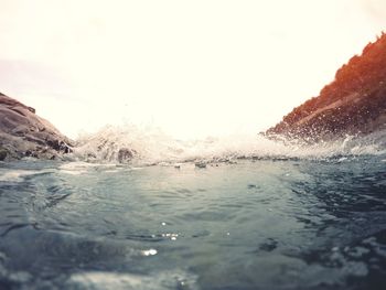 Close-up of waves splashing in sea against clear sky