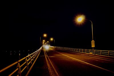 Light trails on bridge against sky at night