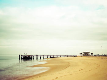 Pier on beach against sky