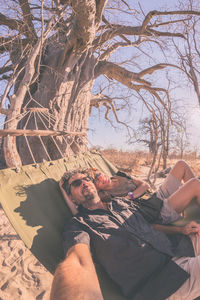 Young couple sitting on bare tree