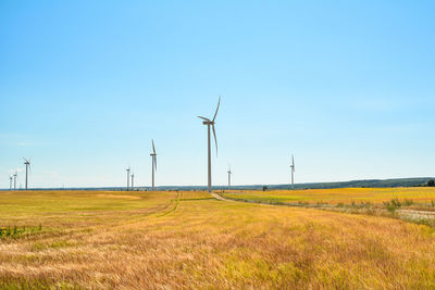 Wind turbines on field against sky