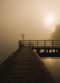 Silhouette pier on footbridge against sky during sunset