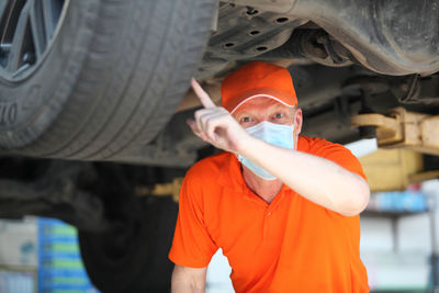 Portrait of man wearing mask repairing car in garage