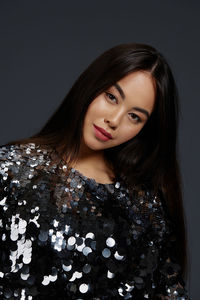 Portrait of young woman standing against black background