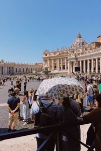 Two people with an umbrella wait in piazza san pietro