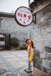 Portrait of woman standing against wall