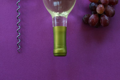 High angle view of wine bottle by grapes on table