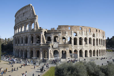 People at coliseum against clear blue sky