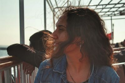 Close-up of young woman looking away against sky