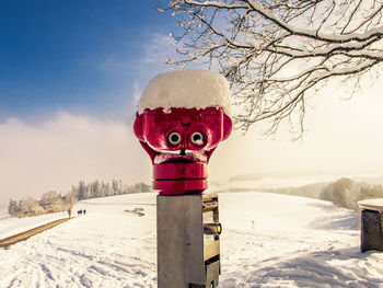 Red umbrella on snow covered field against sky