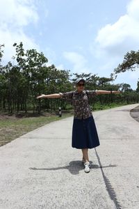 Full length of woman standing on road against sky