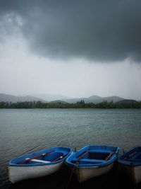 Boats moored in lake against sky