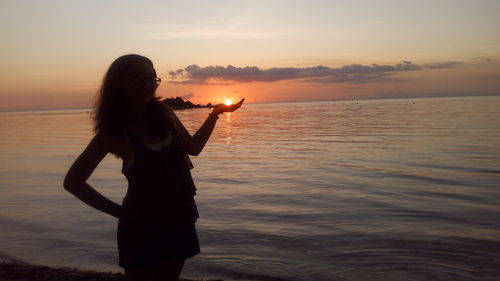 Silhouette woman standing at beach during sunset