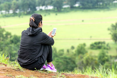 Rear view of young woman moving down on grassy hill