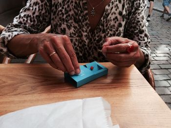 Midsection of woman holding smart phone on table