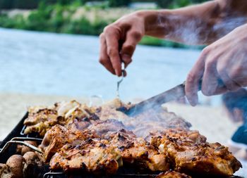 Midsection of person preparing food on barbecue grill