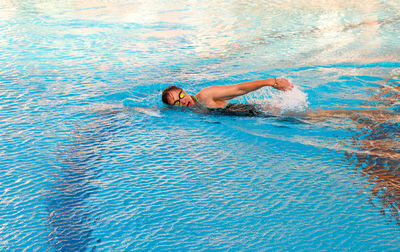 The girl swims in the pool in crawl style