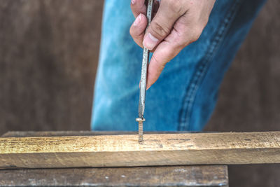 Close-up of man tightening screw on wood