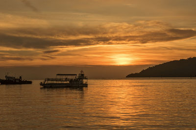 Silhouette boat sailing in sea against sky during sunset