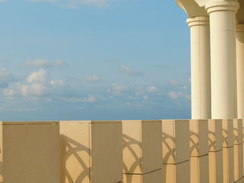 Shadow of railing on beach against sky