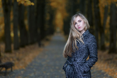 Portrait of young woman standing in forest during autumn