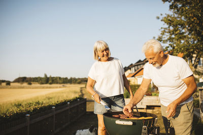 Couple preparing food on grill in garden