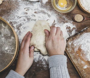 Cropped hands kneading dough on table