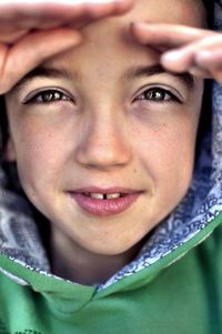 Close-up portrait of teenage boy shielding eyes