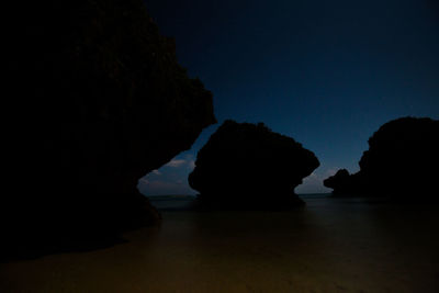 Rock formation in sea against sky at night