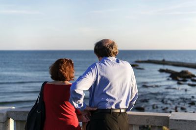 Rear view of people looking at sea against sky