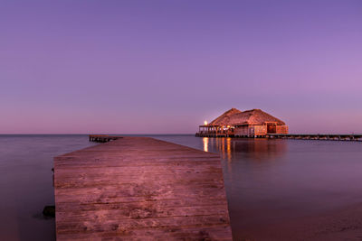 View of building by sea against sky at sunset