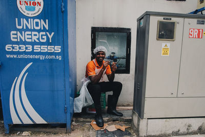 Full length of young man sitting on door