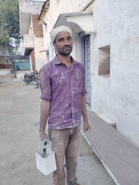 Portrait of young man standing against building