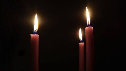 Close-up of illuminated candles in darkroom