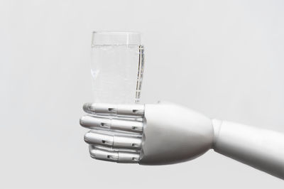 Close-up of hand holding glass against white background