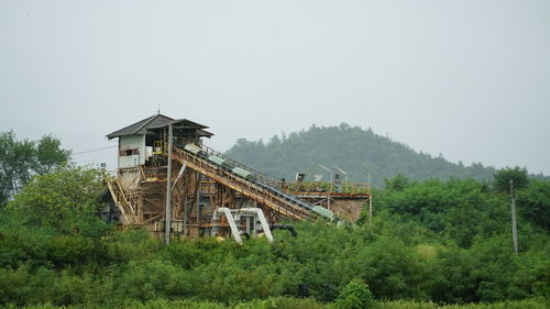 Old industrial facility structure on land against sky and mountain