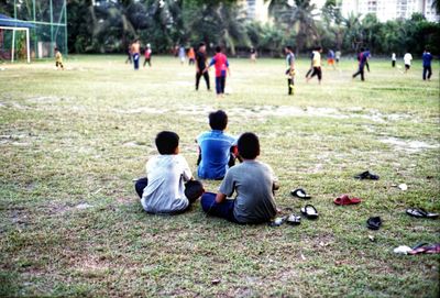 Rear view of people playing on grassland