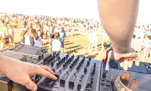 Cropped image of dj using sound mixer with crowd in background during event