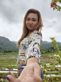 Portrait of beautiful woman smiling on field against sky