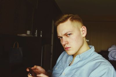 Portrait of young man using mobile phone at home