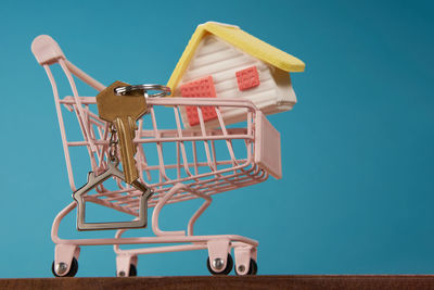 Close-up of shopping cart against blue background