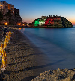 Sunset time in tropea, tricolour flag on the island in front of the city