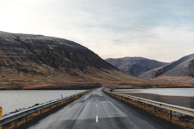 Road by mountains against sky